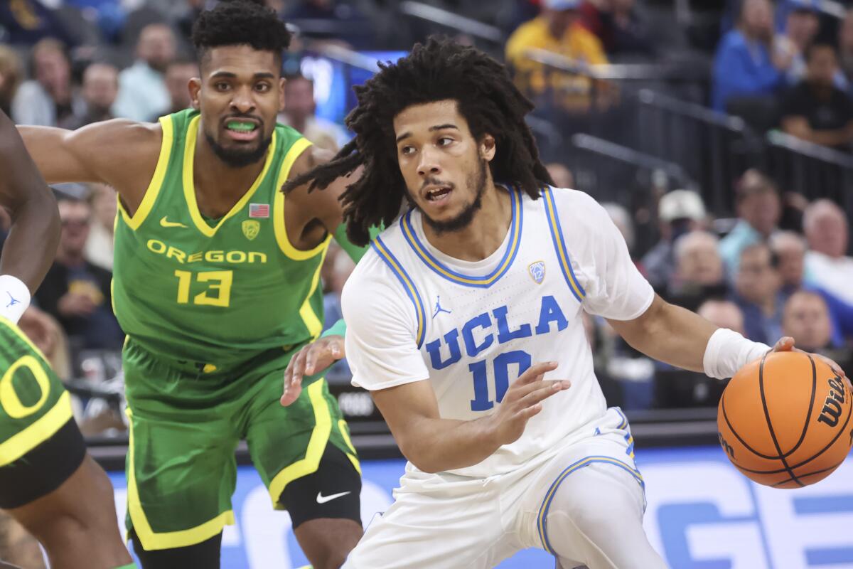 UCLA guard Tyger Campbell drives to the basket in front of Oregon forward Quincy Guerrier.