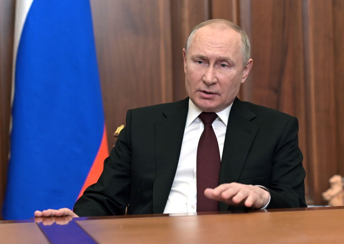 Vladimir Putin speaks from behind a desk.