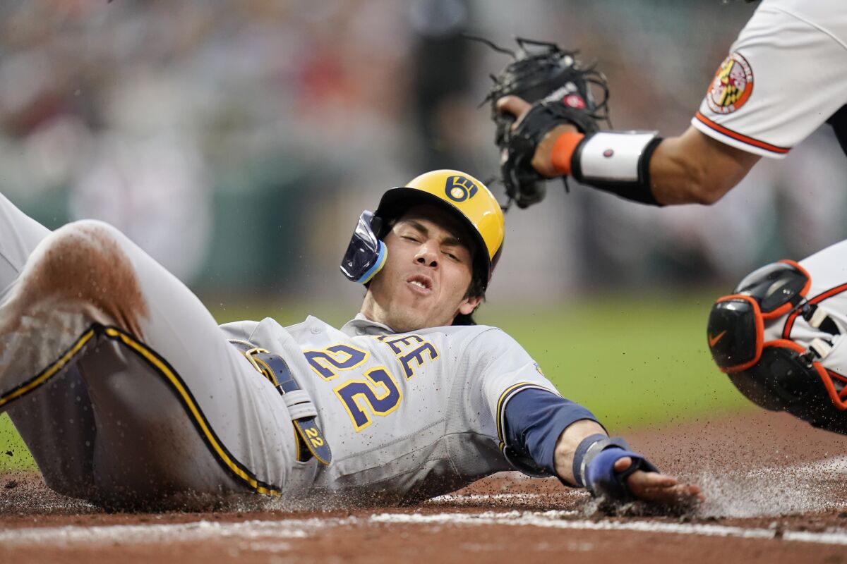 Milwaukee Brewers' Christian Yelich slides in ahead of the tag by Baltimore Orioles catcher Robinson Chirinos while scoring on a double by Andrew McCutchen during the first inning of a baseball game, Tuesday, April 12, 2022, in Baltimore. Brewers' Willy Adames also scored on the play. (AP Photo/Julio Cortez)