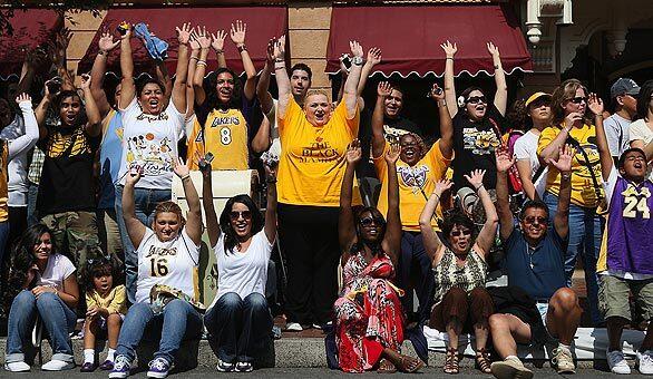 Laker fans do the wave as they wait to see Kobe Bryant parade down Main Street in Disneyland.
