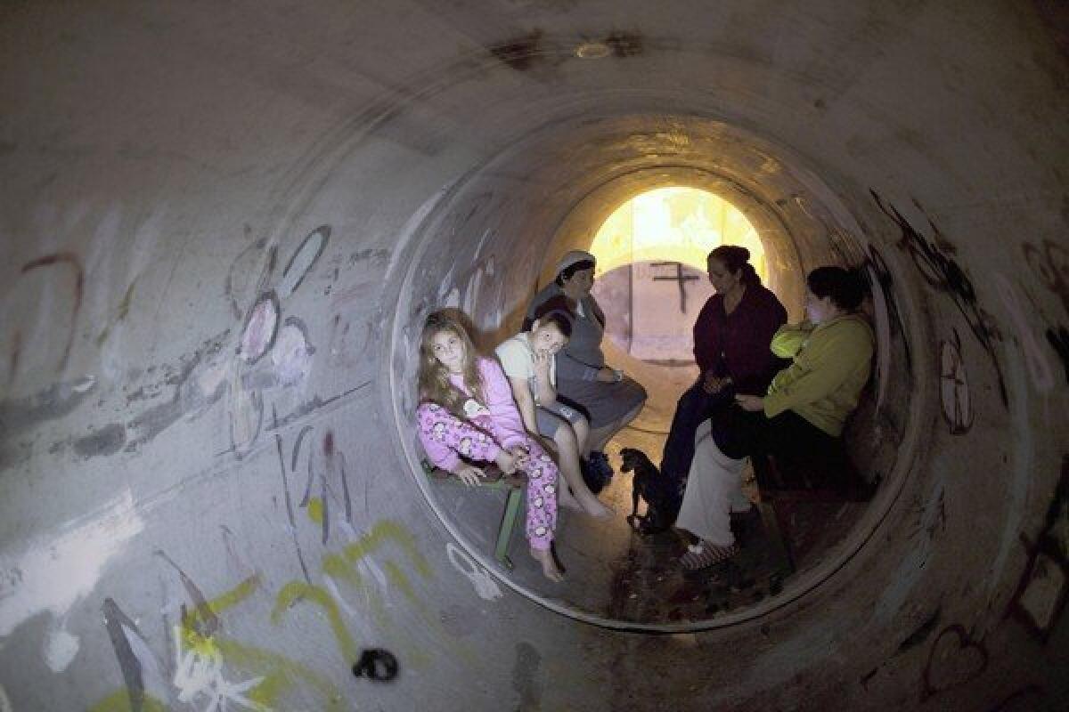 Israelis take cover in a concrete pipe used as a bomb shelter in Kiryat Malachi. Three residents of an apartment building there were killed by a rocket fired from the Gaza Strip.