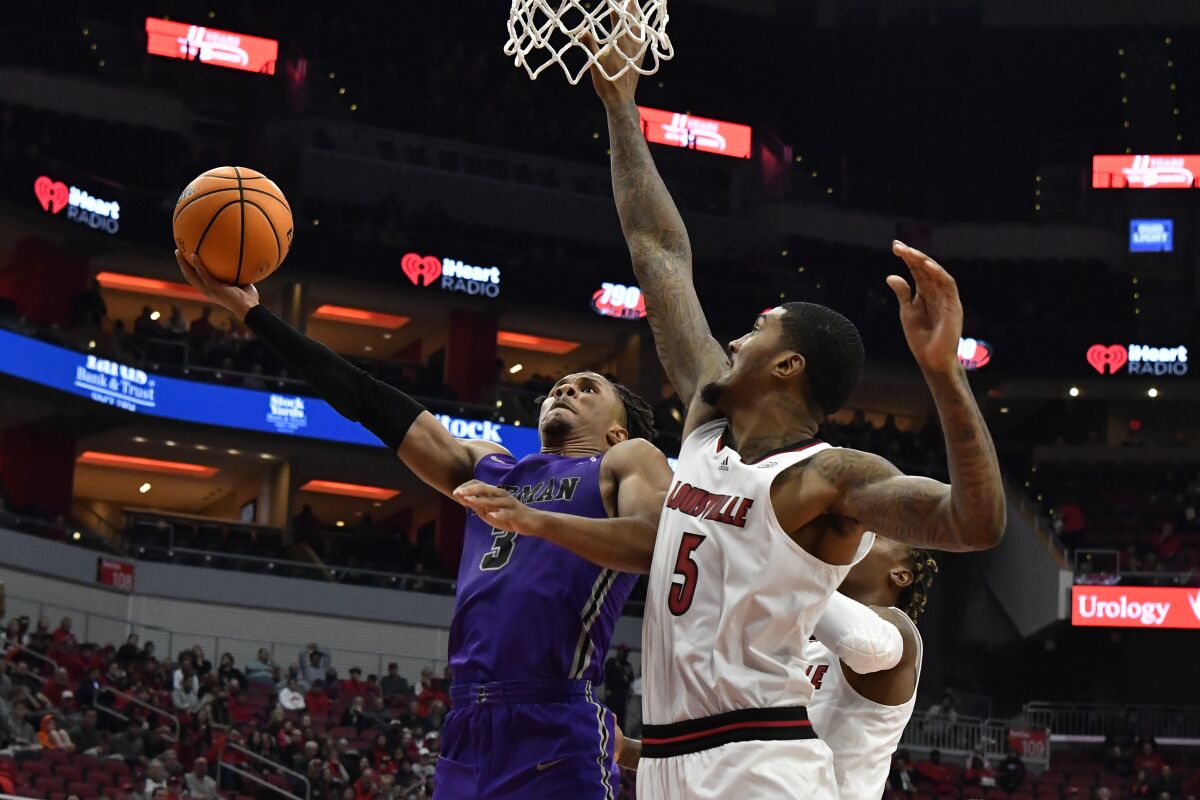 Furman guard Mike Bothwell (3) shoots as Louisville forward Malik Williams (5) defends during the first half of an NCAA college basketball game in Louisville, Ky., Friday, Nov. 12, 2021. (AP Photo/Timothy D. Easley)