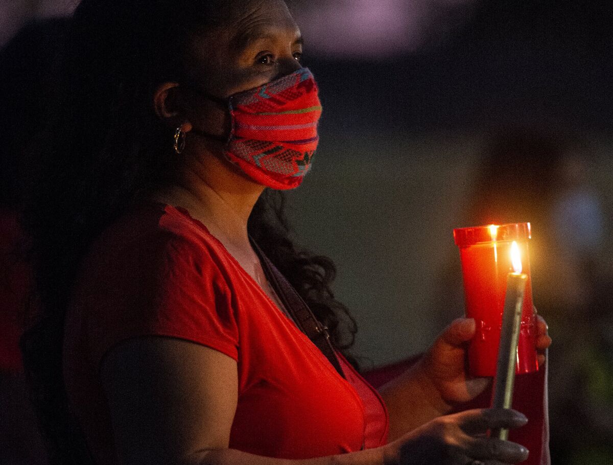 A woman holds a candle at a September vigil for workers at a Foster Farms plant in Livingston, Calif., who died of COVID-19