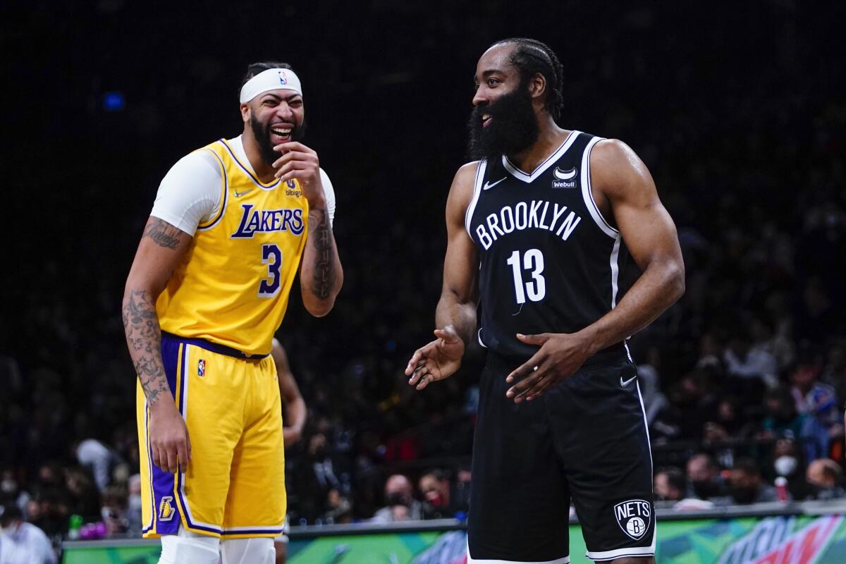 Lakers forward Anthony Davis, left, shares a laugh with Brooklyn Nets guard James Harden.