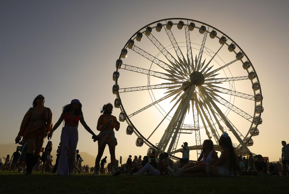 Three people and a Ferris wheel are silhouetted against a twilight sky.