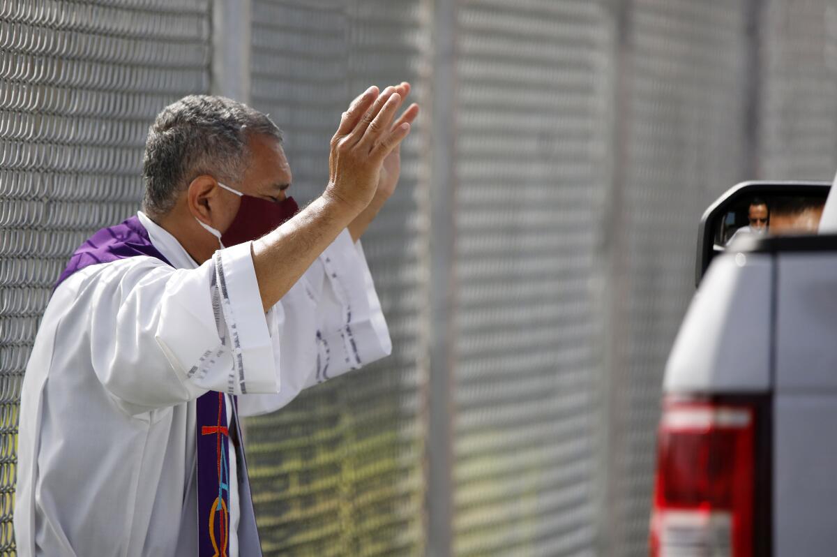 Father Douglas Zavala of St. Joachim Catholic Church performs a drive-through confession in Costa Mesa on May 23.