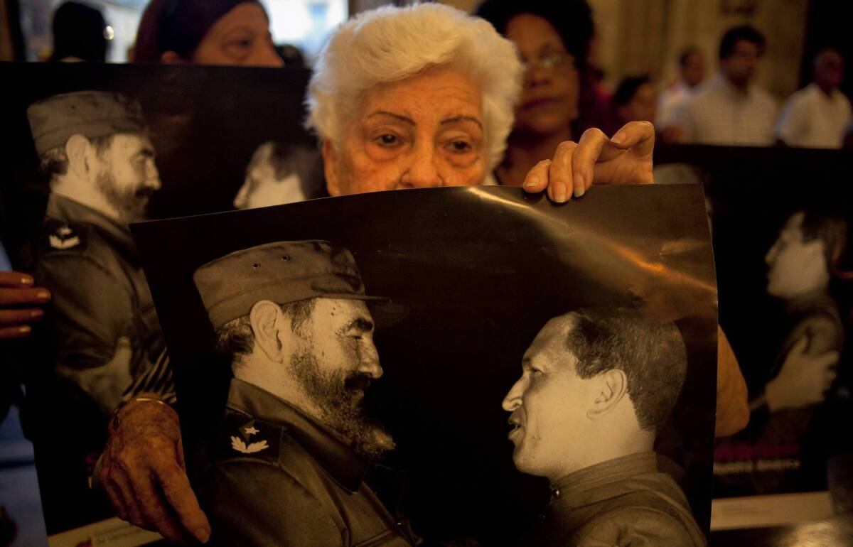 People at a Mass in Havana in January hold posters showing Cuba's Fidel Castro, left, and Venezuelan President Hugo Chavez. The parishioners were praying for the recovery of Chavez, who has cancer.