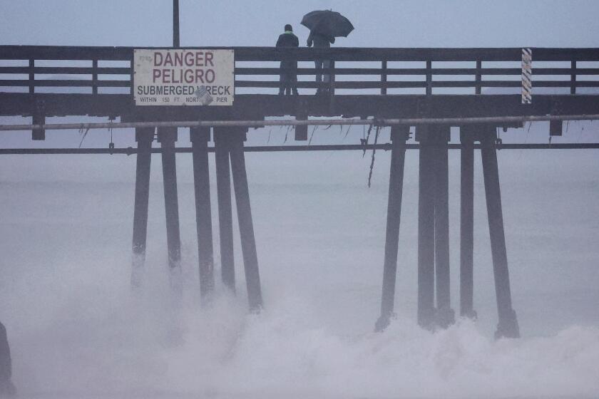 IMPERIAL BEACH, CALIFORNIA - AUGUST 20: People stand on a pier over the Pacific Ocean with Hurricane Hilary approaching in San Diego County on August 20, 2023 in Imperial Beach, California. Southern California is under a first-ever tropical storm warning as Hurricane Hilary approaches with parts of California, Arizona, and Nevada preparing for flooding and heavy rains. All California state beaches have been closed in San Diego and Orange counties in preparation for the impacts from the hurricane. (Photo by Mario Tama/Getty Images)