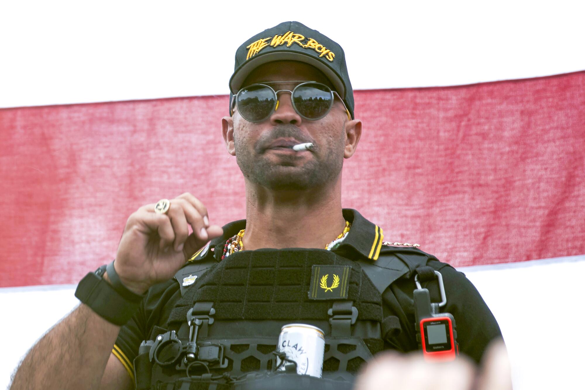 Former extremist leader Henry "Enrique" Tarrio smokes while wearing a tactical vest and hat that reads "The War Boys"