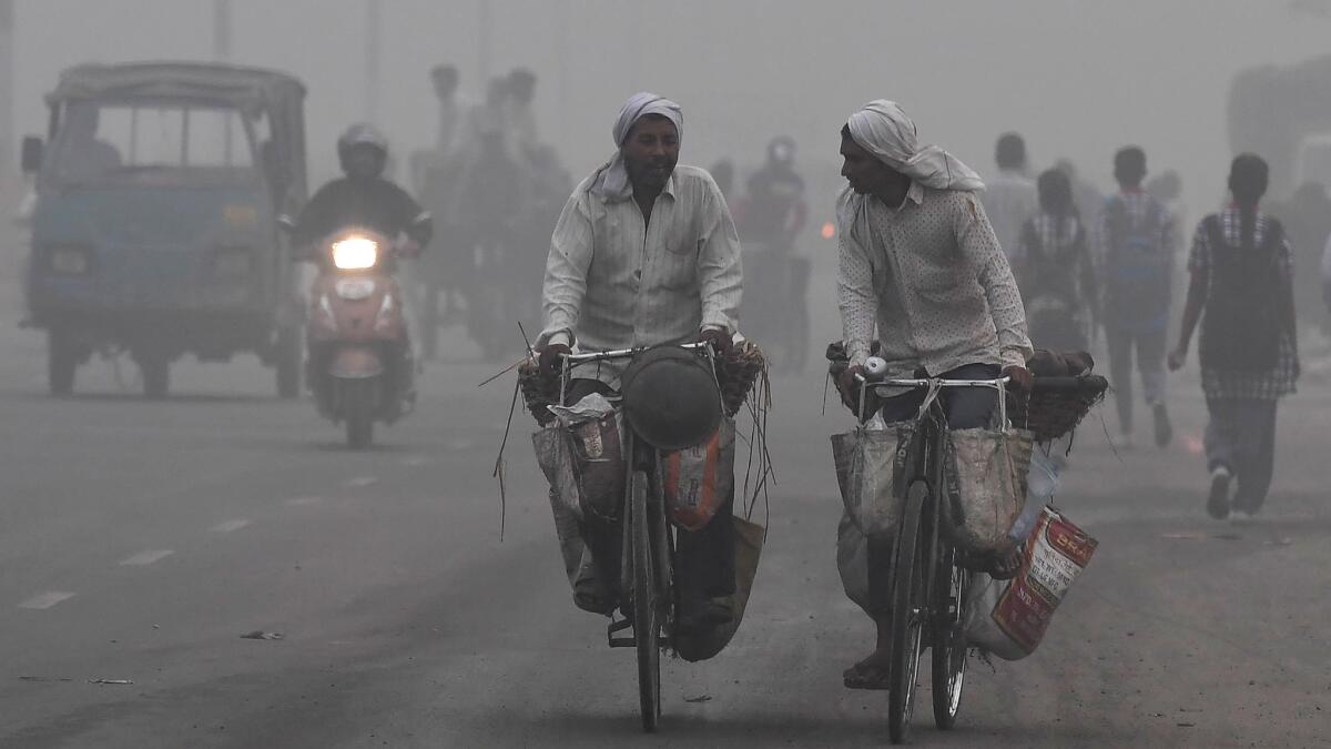 Indian commuters ride amid heavy smog in New Delhi.