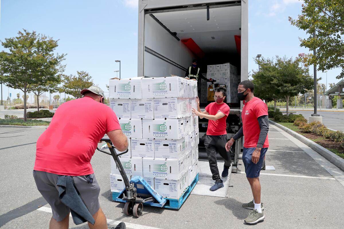 Volunteers unload a crate of Worldwide Produce pre-boxed groceries for 1,000 families during a drive-through food giveaway.