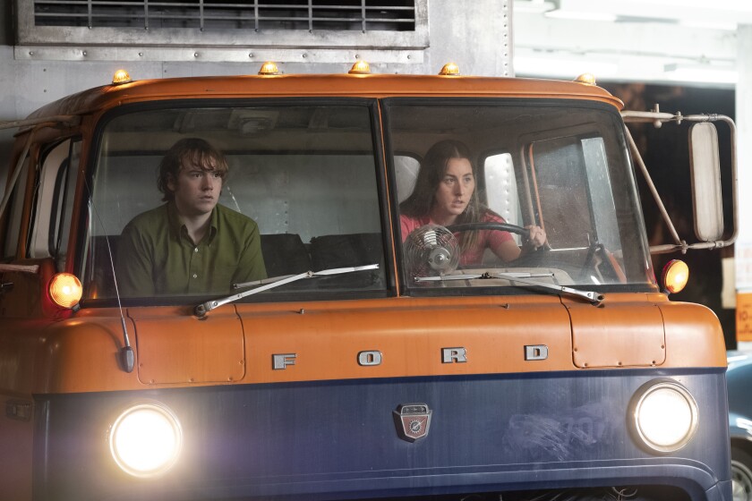 A young man and woman in the cab of a semi-truck.