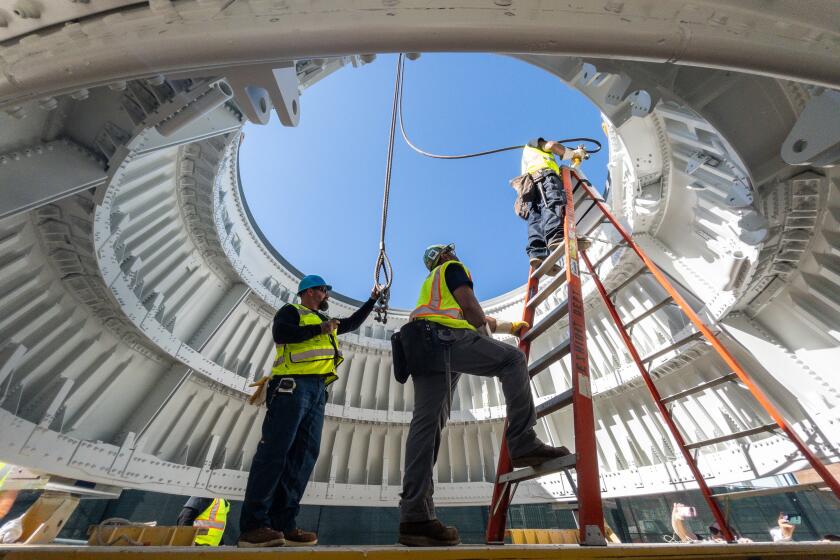 LOS ANGELES, CA - JULY 20: Crews attach cables to a Solid Rocket Booster aft skirt on Thursday, July 20, 2023. Two of these were placed onto seismic isolator pads at the site of the Samuel Oschin Air and Space Center at Exposition Park in Los Angeles, CA. This is the first step in a six-month process of stacking the solid rocket motors, the external tank and finally the space shuttle Endeavour. The vertical exhibit will be 183 feet tall when completed. (Myung J. Chun / Los Angeles Times)