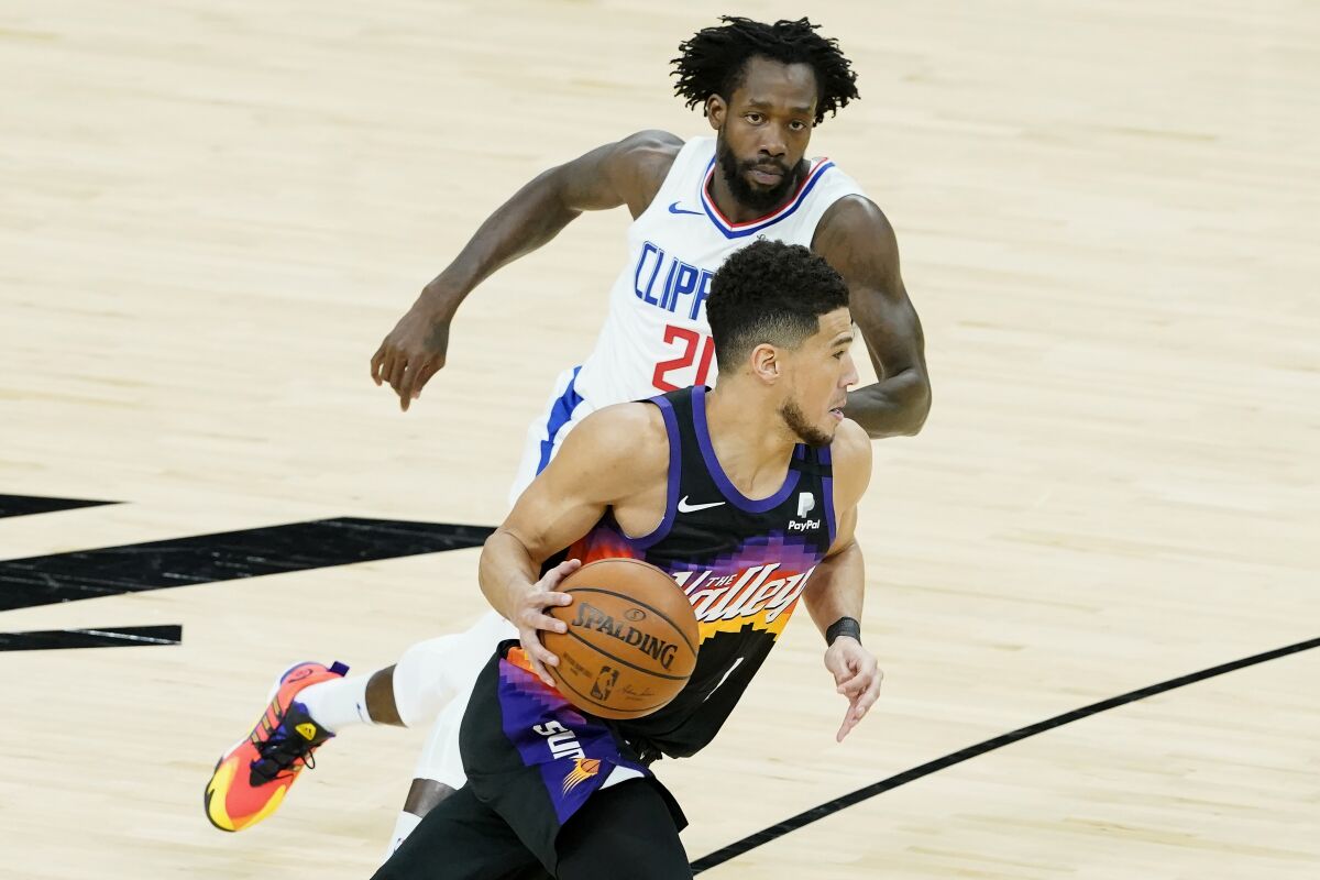 Devin Booker dribbles against Patrick Beverley during the first half.