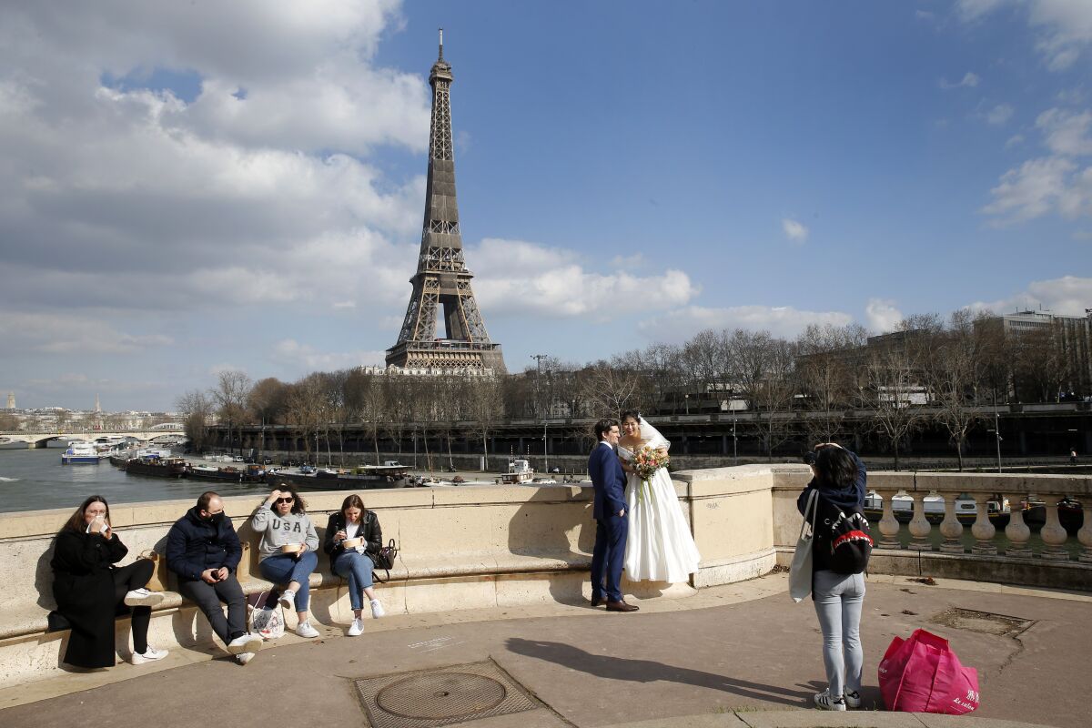 A newly married couple poses in front of the Eiffel Tower in Paris.