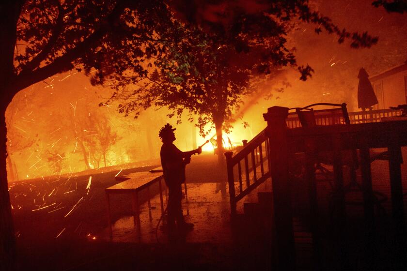 Matt Nichols sprays water while trying to save his home as the LNU Lightning Complex fires tear through Vacaville, Calif., on Wednesday, Aug. 19, 2020. Fire crews across the region scrambled to contain dozens of wildfires sparked by lightning strikes as a statewide heat wave continues. (AP Photo/Noah Berger)