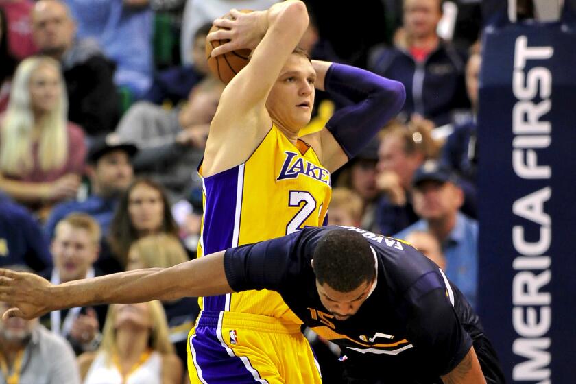 Lakers center Timofey Mozgov grabs a rebound against Jazz forward Derrick Favors during a game Oct. 28.