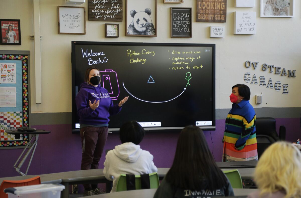 A teacher stands in front of a digital blackboard in her classroom