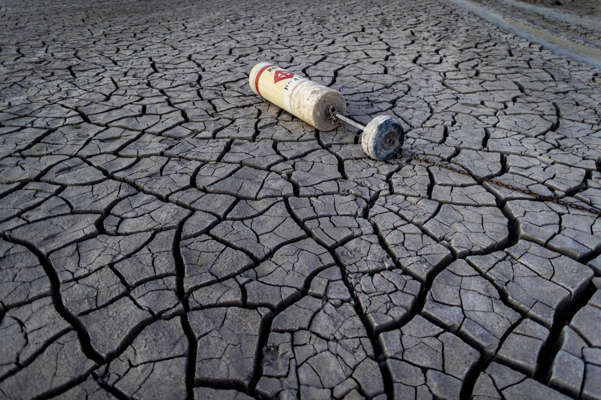 A buoy lies on a dried mud flat 