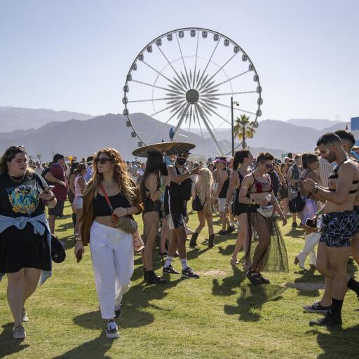 Dozens of people walk in front of a Ferris wheel at Coachella