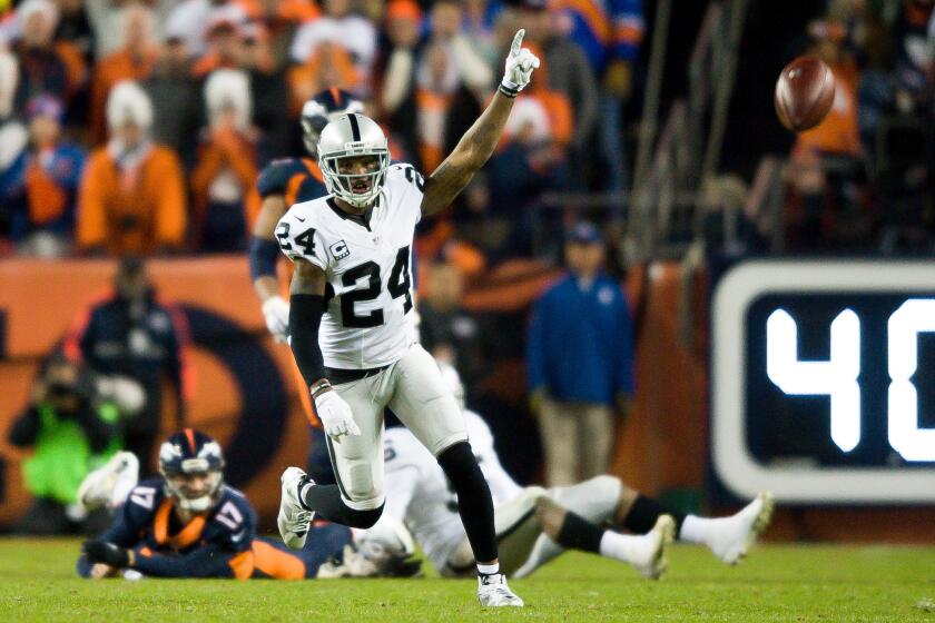 Raiders safety Charles Woodson celebrates a game-sealing play as Broncos quarterback Brock Osweiler lies on the ground after being hit on an incomplete pass.