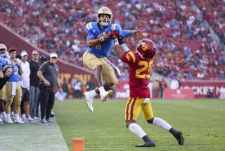 UCLA quarterback Dorian Thompson-Robinson, left, leaps in attempt to get past USC safety Xavion Alford