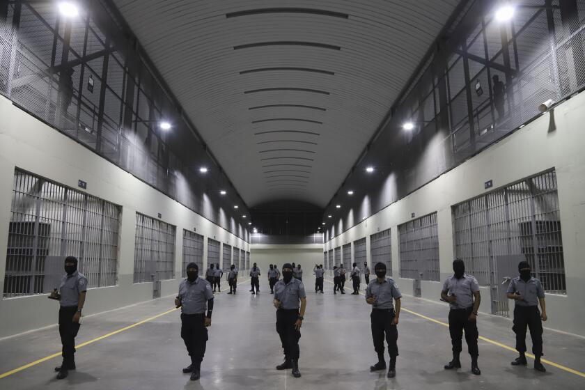 Civil guards from the General Directorate of Prisons stand outside holding cells at The Terrorism Confinement Center during a media tour in Tecoluca, El Salvador Thursday, Feb. 2, 2023. The "mega-prison" still under construction has a maximum capacity of 40,000 and is intended to imprison gang members, according to the government. (AP Photo/Salvador Melendez)