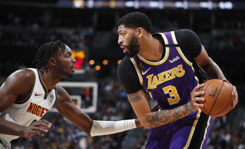 Los Angeles Lakers forward Anthony Davis, right, looks to pass the ball as Denver Nuggets forward Jerami Grant defends during the first half of an NBA basketball game Wednesday, Feb. 12, 2020, in Denver. (AP Photo/David Zalubowski)