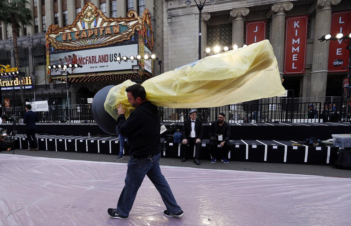 Adrian Puccio carries an Oscar statue to the red carpet along Hollywood Boulevard. Forecasters say rain could fall Sunday during the 87th Academy Awards.