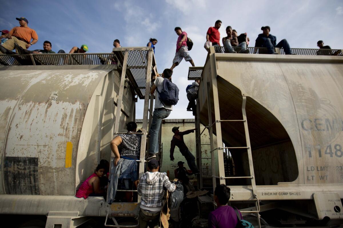 Central American migrants climb on a northbound train in Ixtepec, Mexico, on Saturday during their journey toward the U.S. border.
