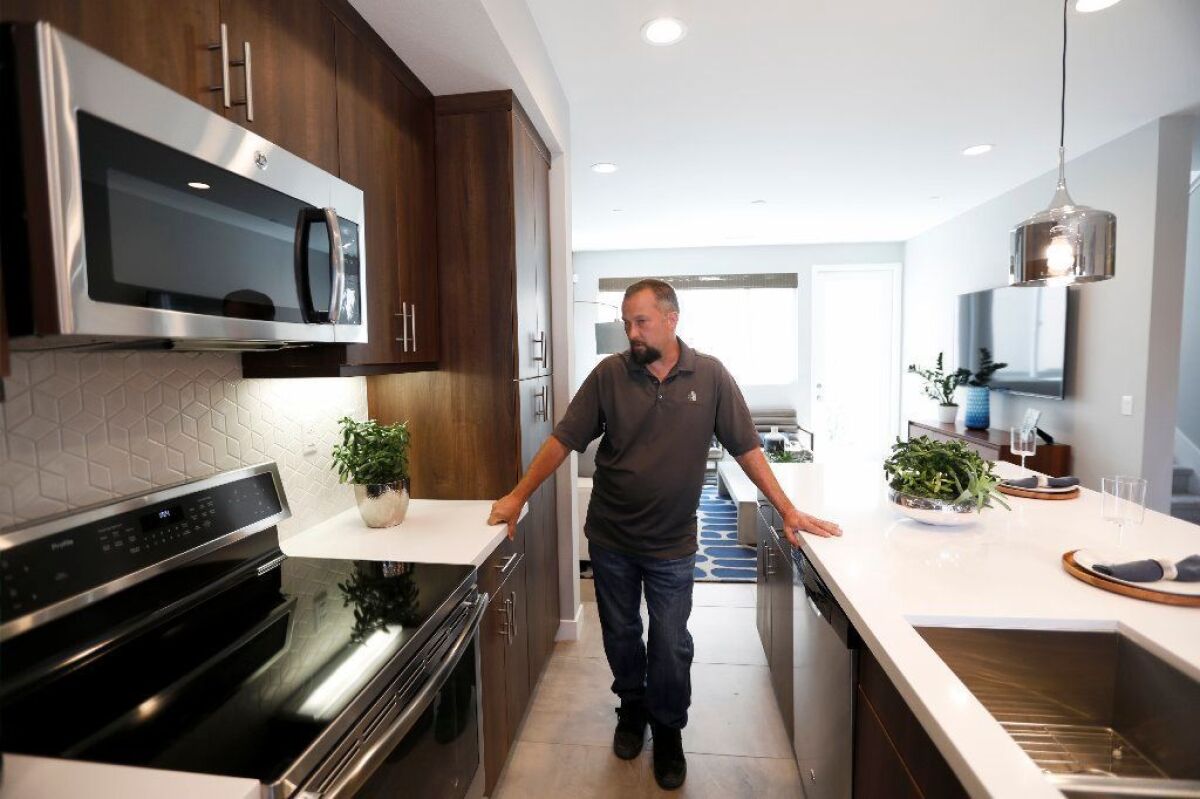 Construction manager Chris Smith shows off an induction cooktop at an all-electric, solar-powered town home development being built by City Ventures in Bellflower in March.