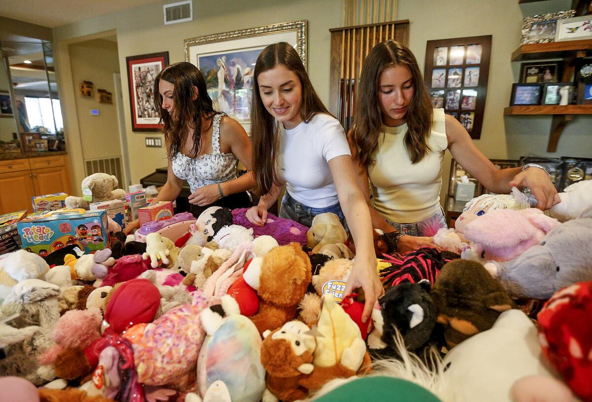 Jessie, Cassie and Alexis Ross, from left, organize dozens of various toys at their home in Huntington Beach on Thursday. 