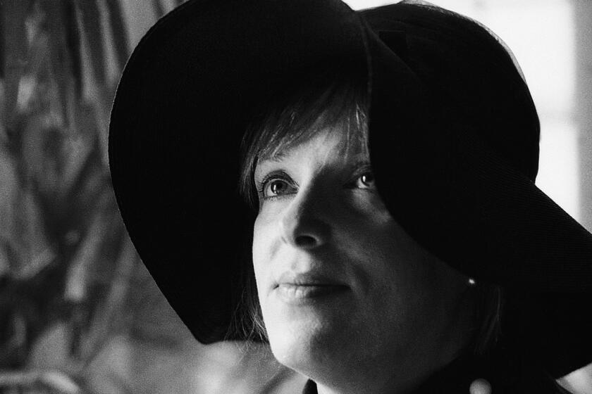 A black and white photo of a woman wearing a black floppy hat.