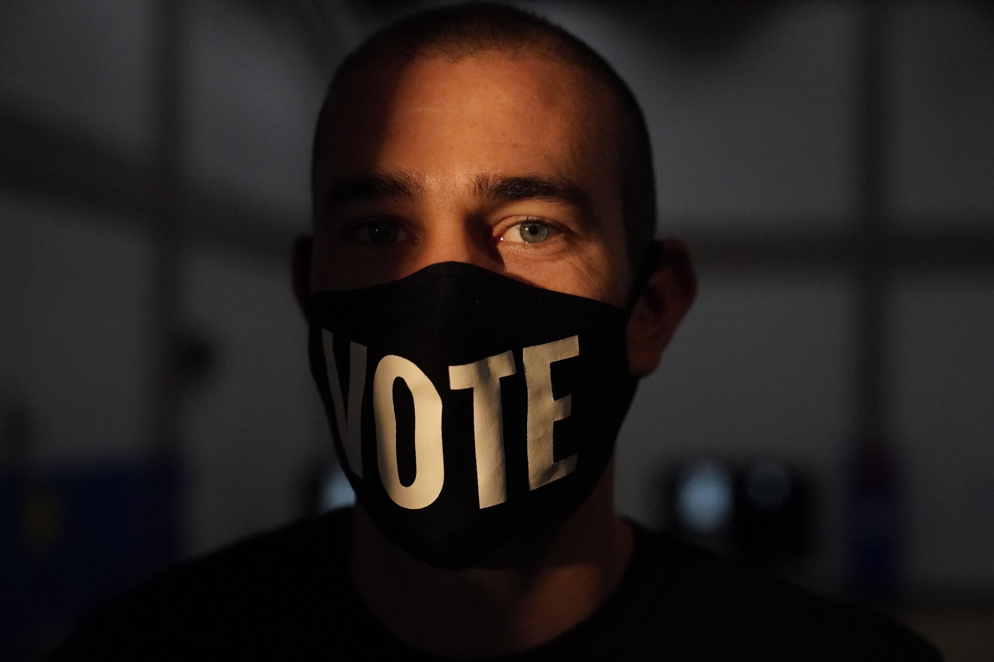A closeup of a person wearing a mask that says "Vote."