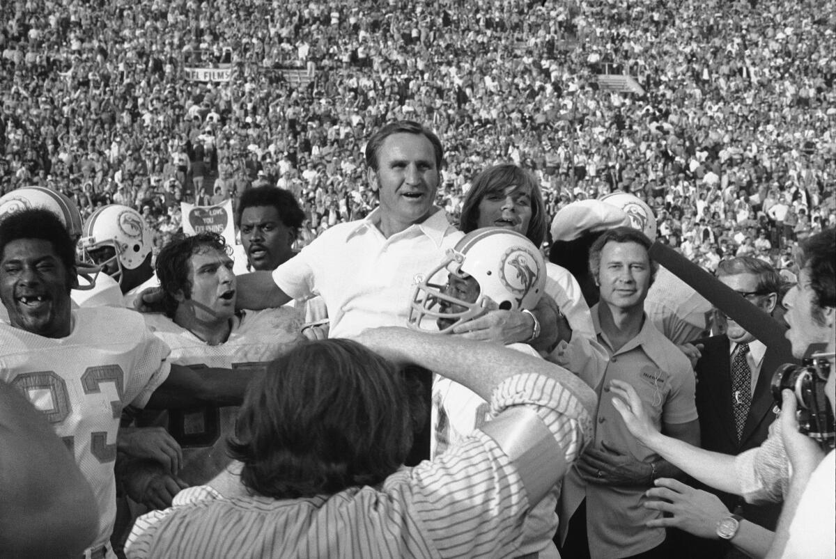 A smiling Miami Dolphins Coach Don Shula is carried off the field after his team won Super Bowl VII.