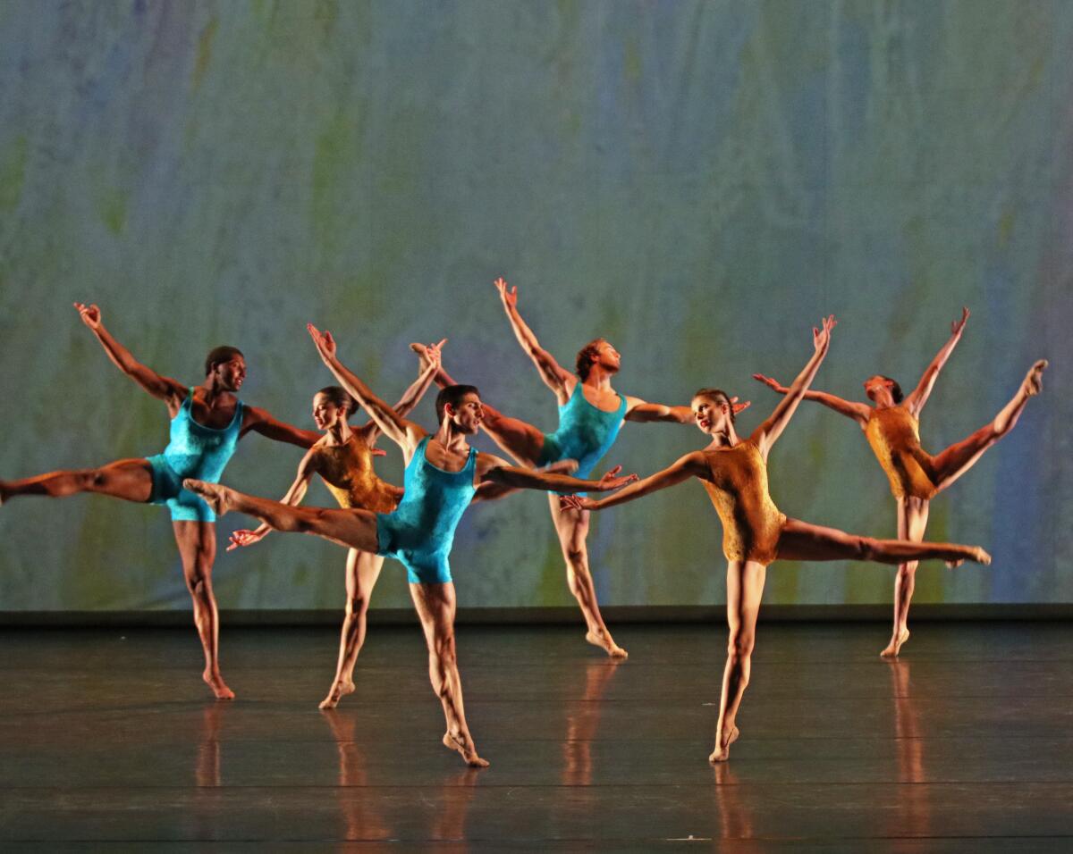 Dancers on a stage with extended arms and legs.