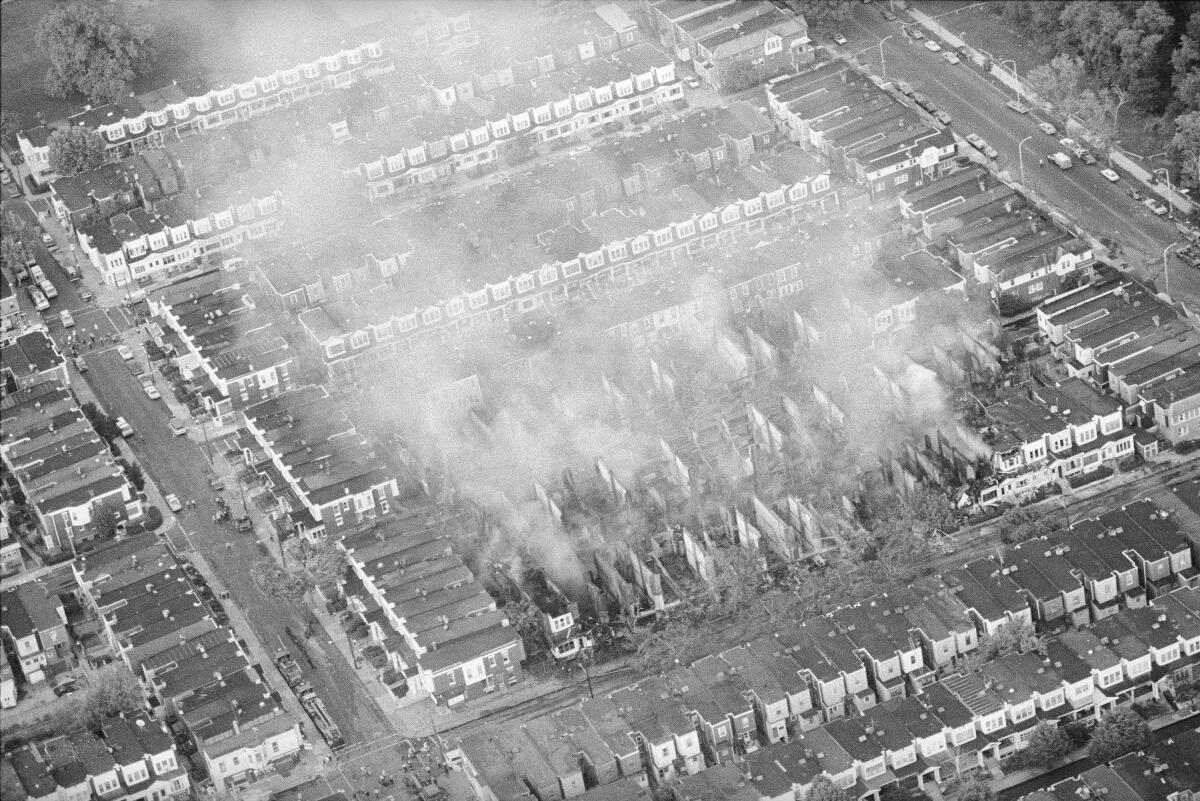FILE - Smoke rises from the ashes of a West Philadelphia neighborhood, May 4, 1985, the morning after a siege between Philadelphia police and members of the radical group MOVE left 11 people dead and 61 homes destroyed. The remains of two children killed in the 1985 bombing by police of a Philadelphia home used as the headquarters of a Black radical group have been returned to their brother, the man said Wednesday, Aug. 3, 2022. (AP Photo/Peter Morgan, File)