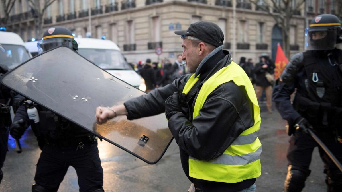 A man punches the shield of a riot police officer on Jan. 19, 2019, in Paris, during a demonstration called by the "yellow vest" movement as part of a nationwide protest against the high cost of living and government tax reforms.