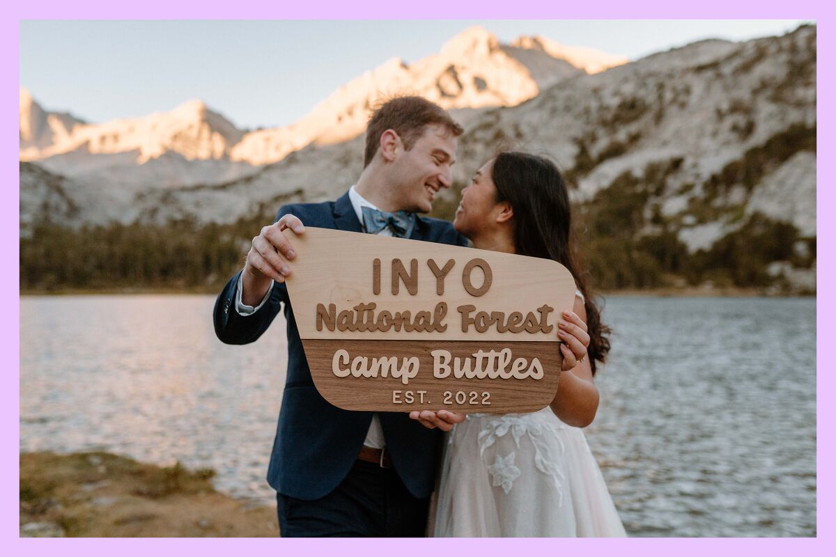 Camille and Robert Buttles pose with a "Camp Buttles" National Forest sign.