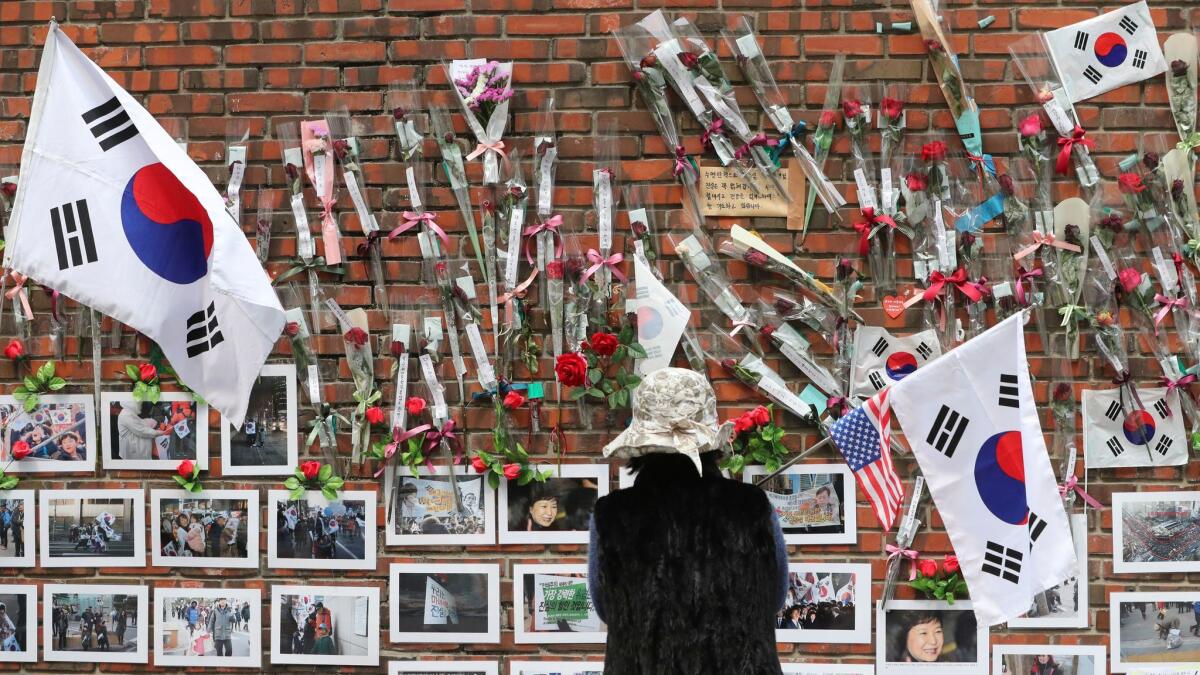 A supporter of former South Korean President Park Geun-hye looks at photos of Park on a wall of her private home in Seoul on March 27.