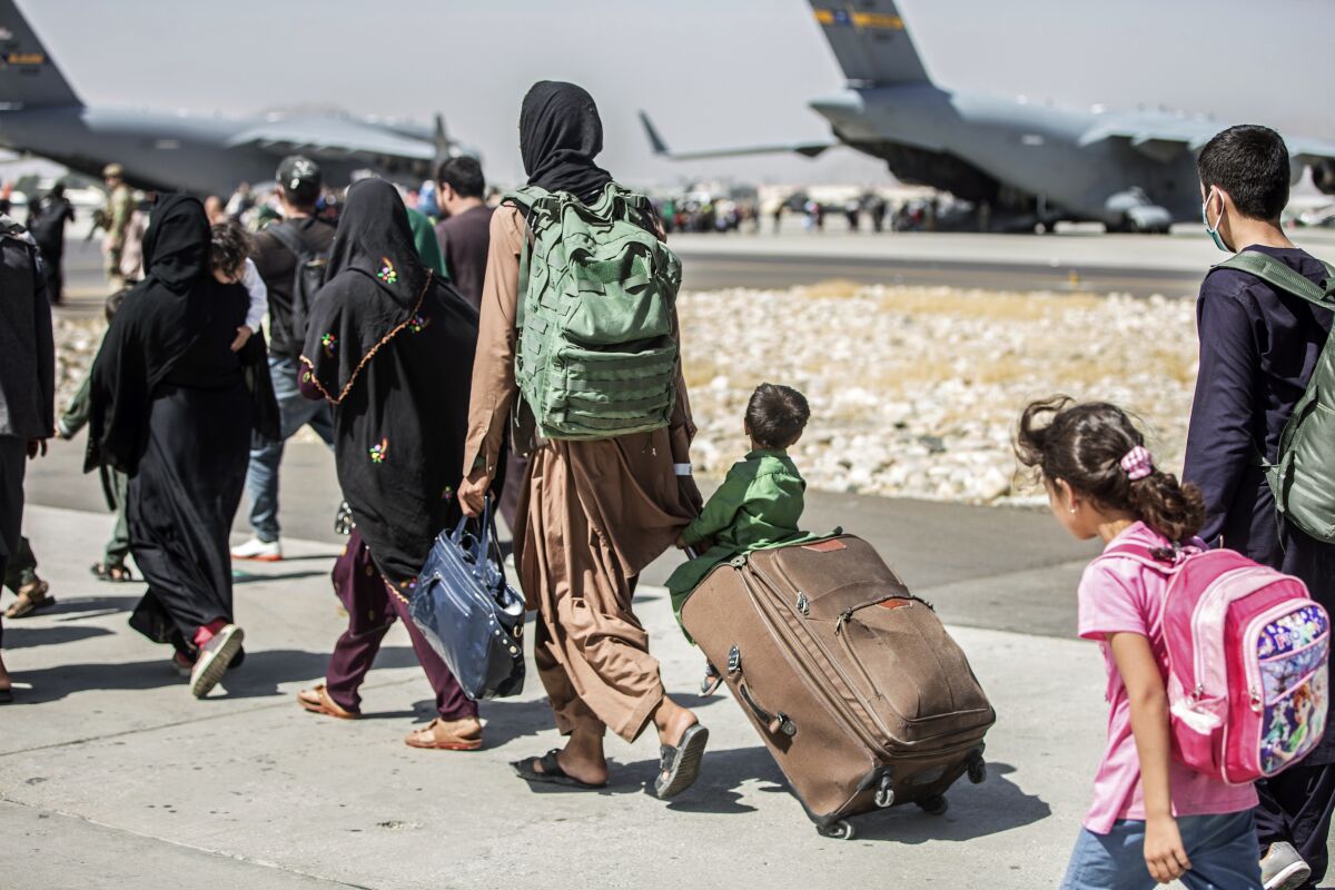 FILE - In this Aug. 24, 2021, file photo provided by the U.S. Marine Corps, families walk towards their flight during ongoing evacuations at Hamid Karzai International Airport, in Kabul, Afghanistan. More than 30 California children are stuck in Afghanistan after traveling to the country to see their relatives weeks before the Taliban seized power and US forces left, according to school districts where the kids are enrolled. (Sgt. Samuel Ruiz/U.S. Marine Corps via AP, File)