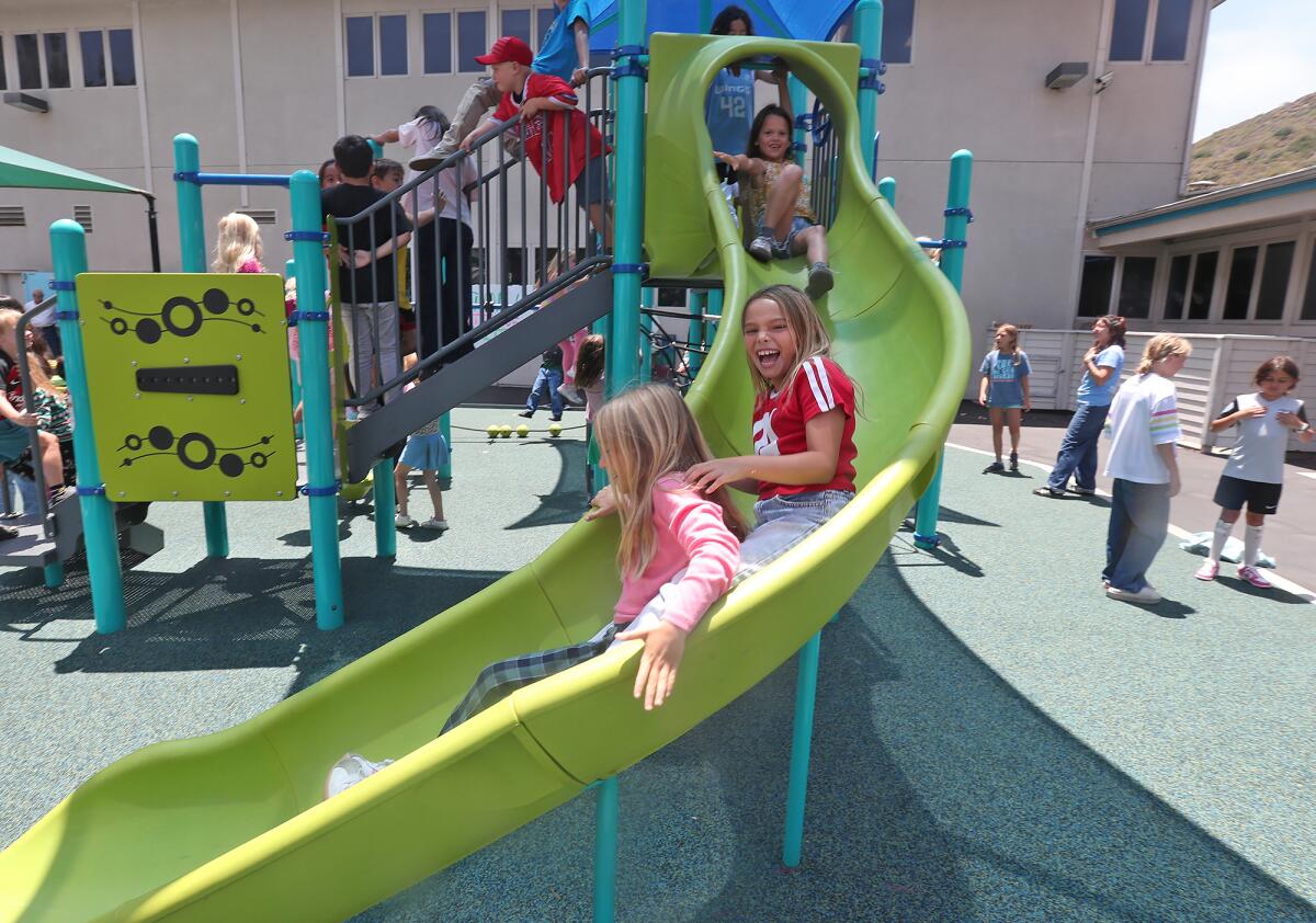 Kids from the Boys & Girls Club of Laguna Beach go down the slide in the Dream Play Yard on Friday.
