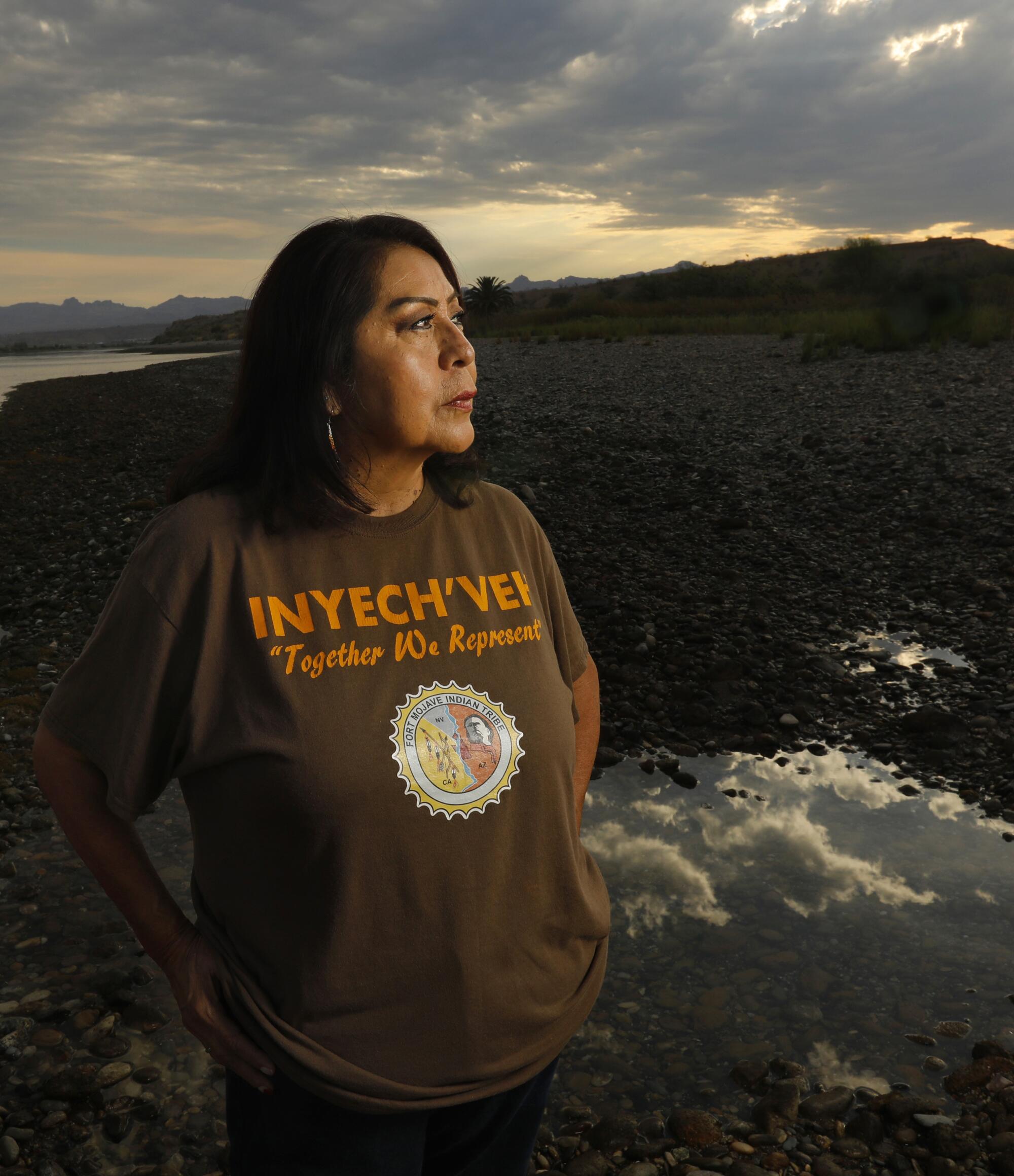 A woman stands along the banks of a river