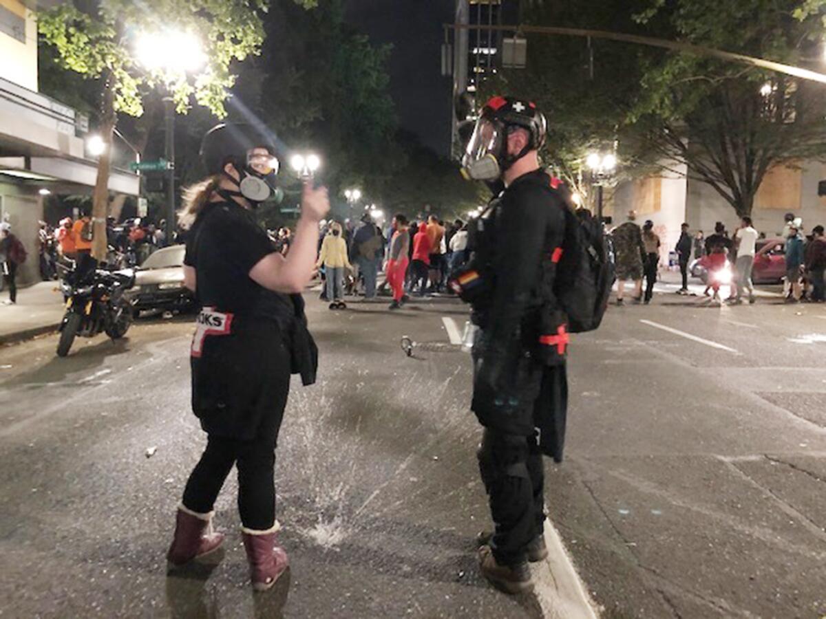 Brooke Hazel, left, gestures to fellow volunteer medic Davis Beeman after caring for a protester injured by tear gas.