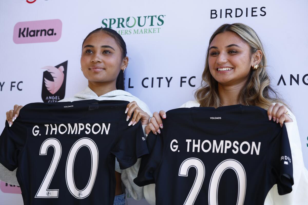 Alyssa Thompson, left, and Gisele Thompson hold up Angel City jerseys at a news conference.