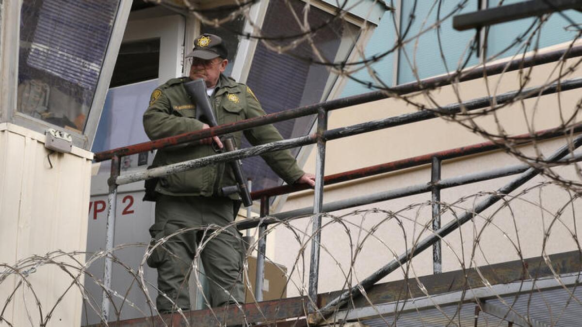 A guard watches prisoners being escorted across the yard at San Quentin State Prison.