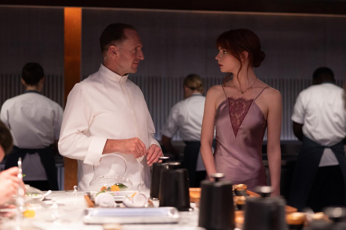 A male chef and a young woman in a dress in the movie "The Menu."