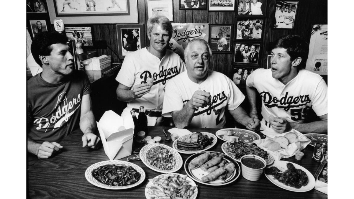 Sep. 28, 1985: The raucous pre- and postgame meals are a tradition in Tommy Lasorda's office. Joining the great eater in a slight snack of Chinese and Italian food are, from left, Steve Sax, Jerry Reuss and Orel Hershiser.