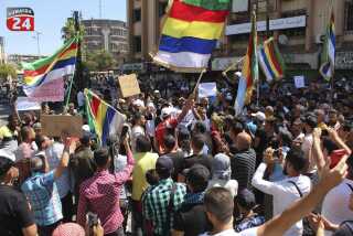 In this photo released on Sunday, Aug. 27, 2023, by Suwayda24, people stage a protest as they wave the Druze flags in the southern city of Sweida, Syria. Anti-government protests have rocked south Syria for the past week. Demonstrators initially took to the streets over surging inflation but are now calling for the ouster of President Bashar Assad, echoing the beginnings of a 2011 uprising that sparked Syria's brutal civil war. (Suwayda24 via AP)