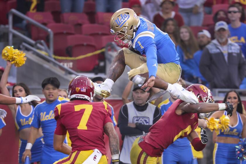 Los Angeles, CA - November 20: UCLA quarterback Dorian Thompson-Robinson hurdles high over USC safety.